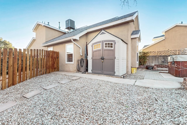 back of house with a patio, a fenced backyard, an outbuilding, a shed, and stucco siding