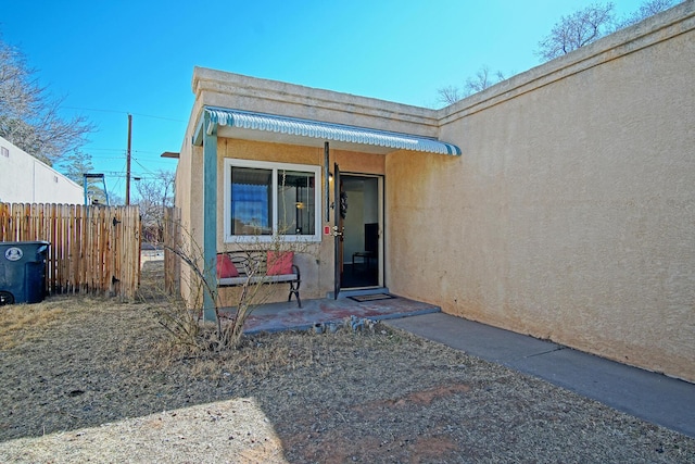 property entrance featuring fence and stucco siding