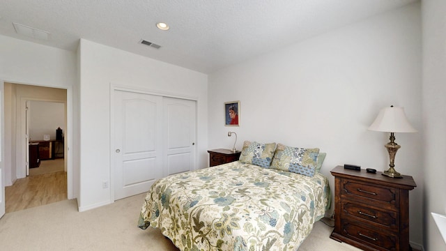 bedroom with light carpet, visible vents, a textured ceiling, a closet, and recessed lighting