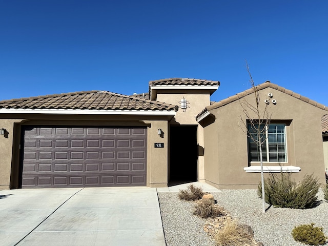 view of front facade with a garage, concrete driveway, a tiled roof, and stucco siding