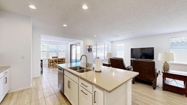 kitchen featuring a center island with sink, white cabinets, dishwasher, light countertops, and a sink