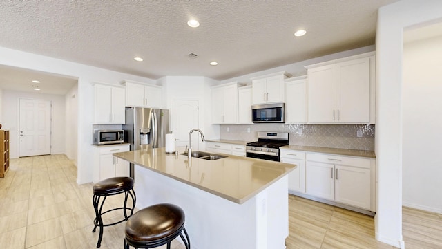 kitchen with white cabinets, a kitchen island with sink, stainless steel appliances, and a sink