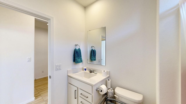 bathroom featuring toilet, baseboards, and vanity