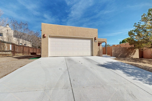 garage featuring concrete driveway and fence