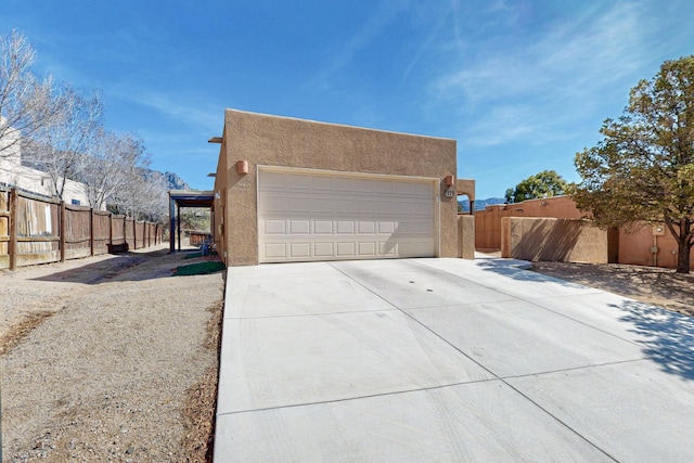 garage featuring concrete driveway and fence