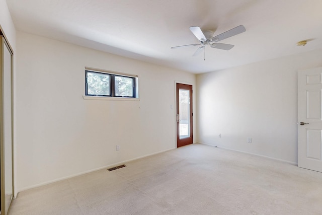 empty room with a ceiling fan, visible vents, light carpet, and baseboards