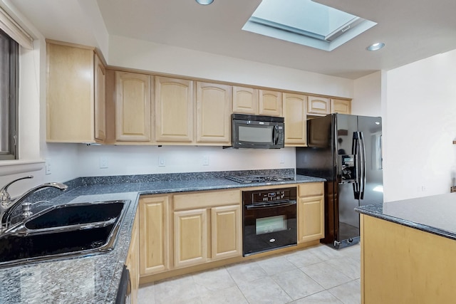 kitchen featuring a skylight, black appliances, light brown cabinets, a sink, and recessed lighting