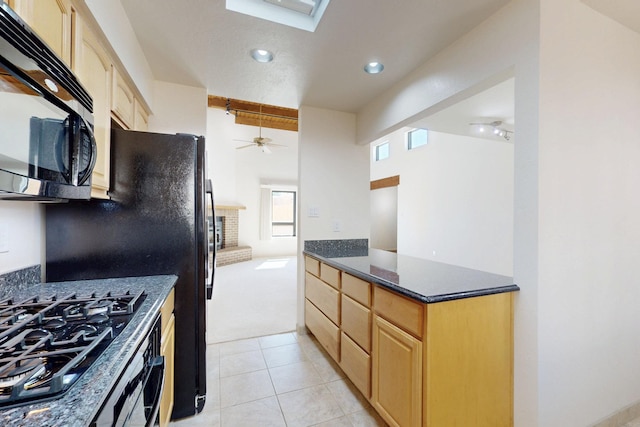 kitchen with black gas cooktop, ceiling fan, light tile patterned floors, light brown cabinets, and a brick fireplace