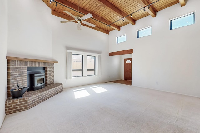 unfurnished living room with carpet floors, a wood stove, wooden ceiling, and beam ceiling