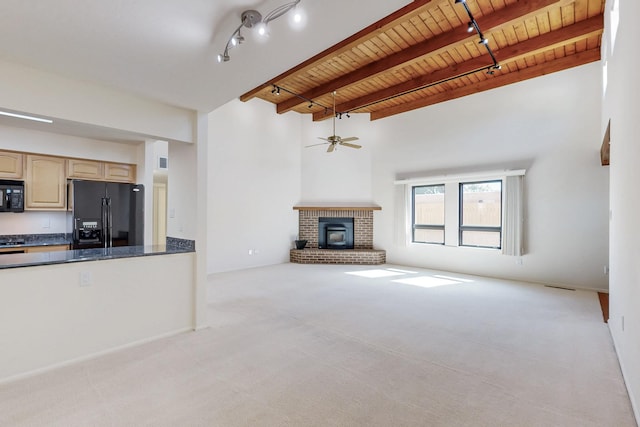 unfurnished living room with light colored carpet, a fireplace, wood ceiling, beam ceiling, and track lighting