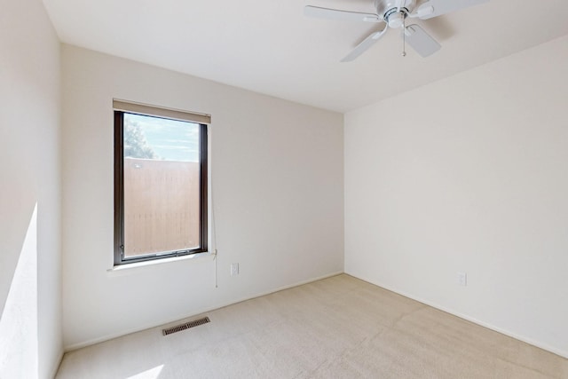 carpeted spare room featuring visible vents and a ceiling fan