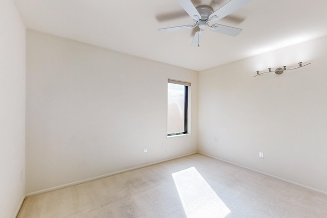 spare room with light colored carpet, ceiling fan, and baseboards