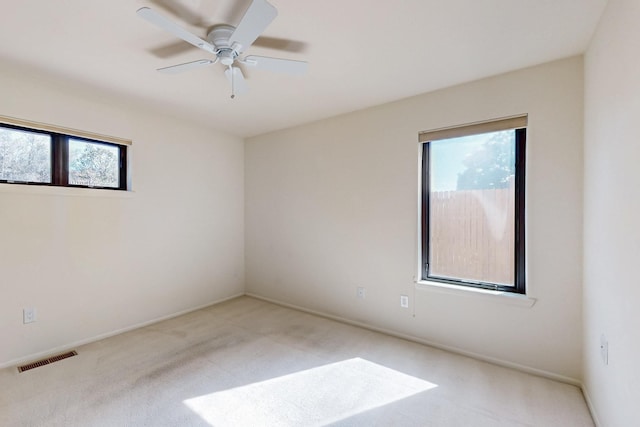 spare room with a ceiling fan, visible vents, and carpet flooring