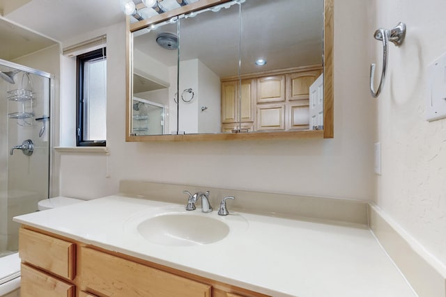 bathroom featuring a shower stall, toilet, and vanity