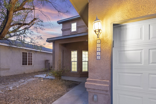 property entrance featuring a garage and stucco siding