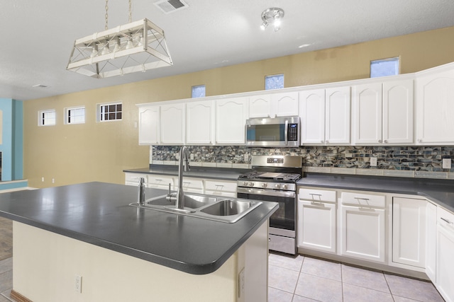 kitchen featuring stainless steel appliances, dark countertops, a sink, and visible vents