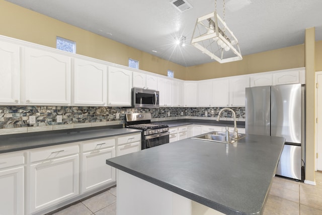 kitchen with dark countertops, visible vents, appliances with stainless steel finishes, and a sink