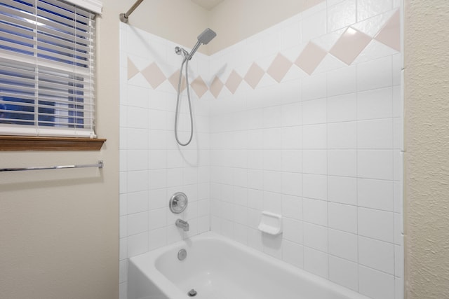 full bathroom with a textured wall and  shower combination