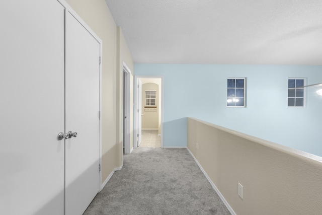 hall featuring carpet flooring, a textured ceiling, and baseboards