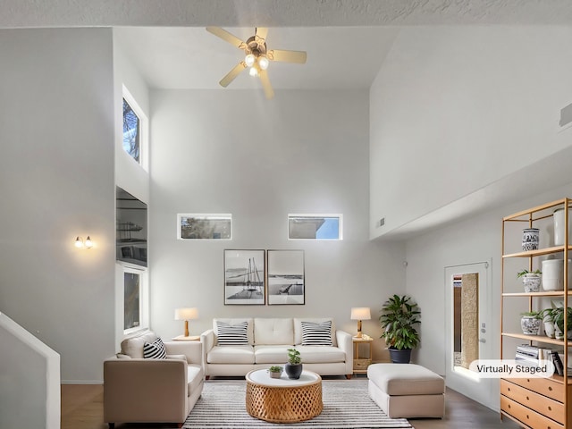 living room with a towering ceiling, visible vents, and a ceiling fan