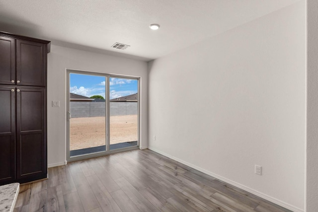 unfurnished bedroom with baseboards, wood finished floors, visible vents, and access to exterior