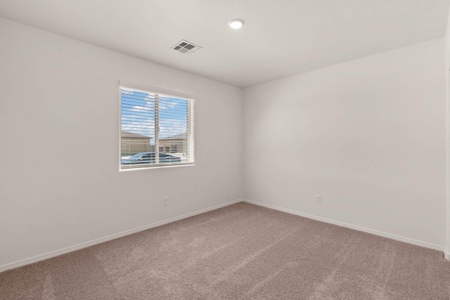 empty room with baseboards, visible vents, and light colored carpet