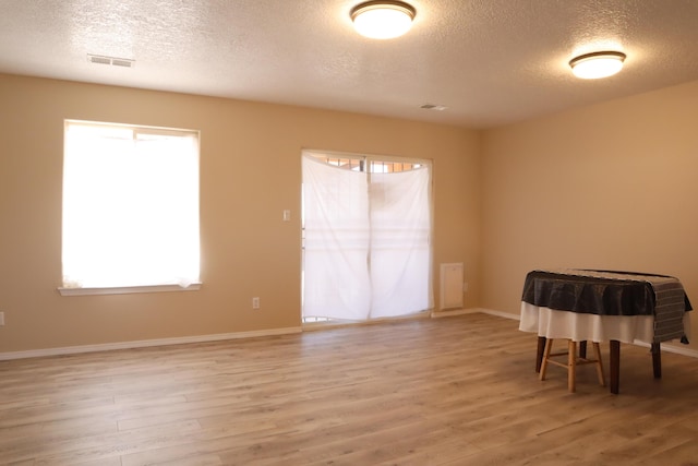 empty room with visible vents, baseboards, a wealth of natural light, and wood finished floors