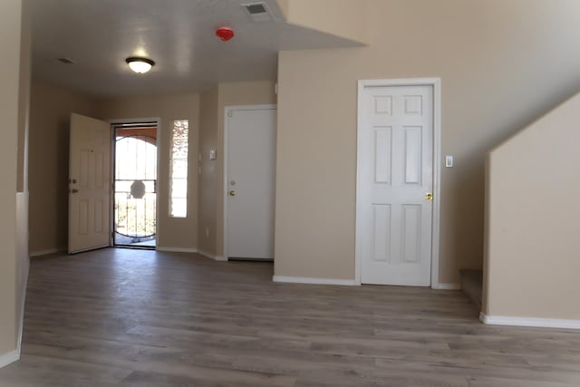 foyer entrance with dark wood finished floors, visible vents, and baseboards