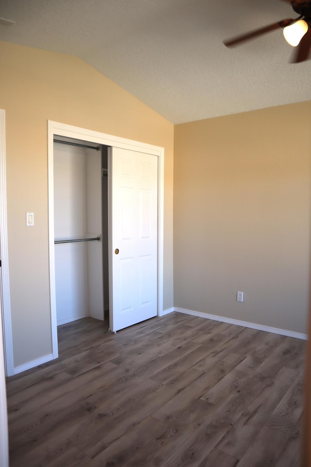 unfurnished bedroom with vaulted ceiling, a closet, dark wood finished floors, and baseboards