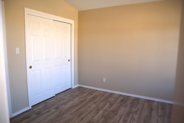 unfurnished bedroom with a closet, baseboards, and dark wood-style flooring