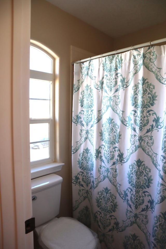 bathroom featuring curtained shower and toilet