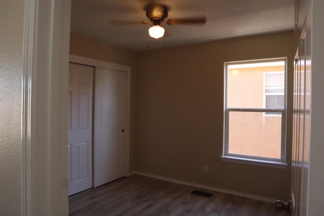 unfurnished bedroom featuring a closet, wood finished floors, visible vents, and baseboards