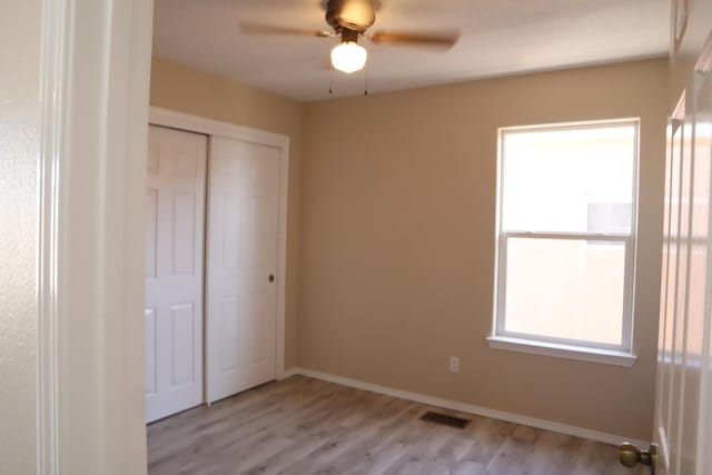 unfurnished bedroom featuring baseboards, light wood-style flooring, visible vents, and a closet