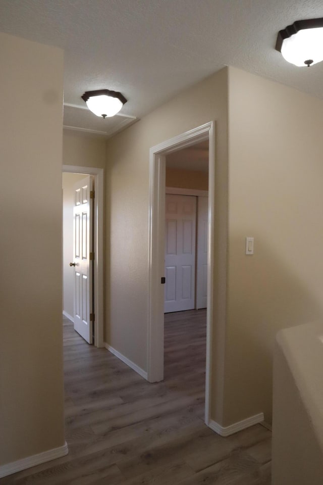 corridor featuring dark wood-style flooring, a textured ceiling, and baseboards