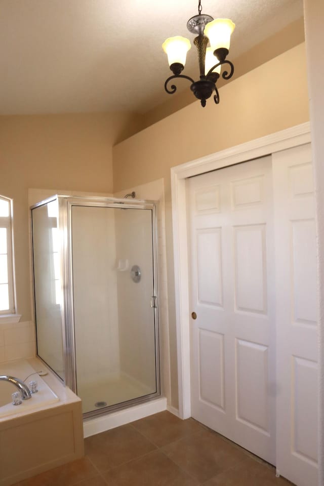 full bath featuring a garden tub, a shower stall, a chandelier, and tile patterned flooring