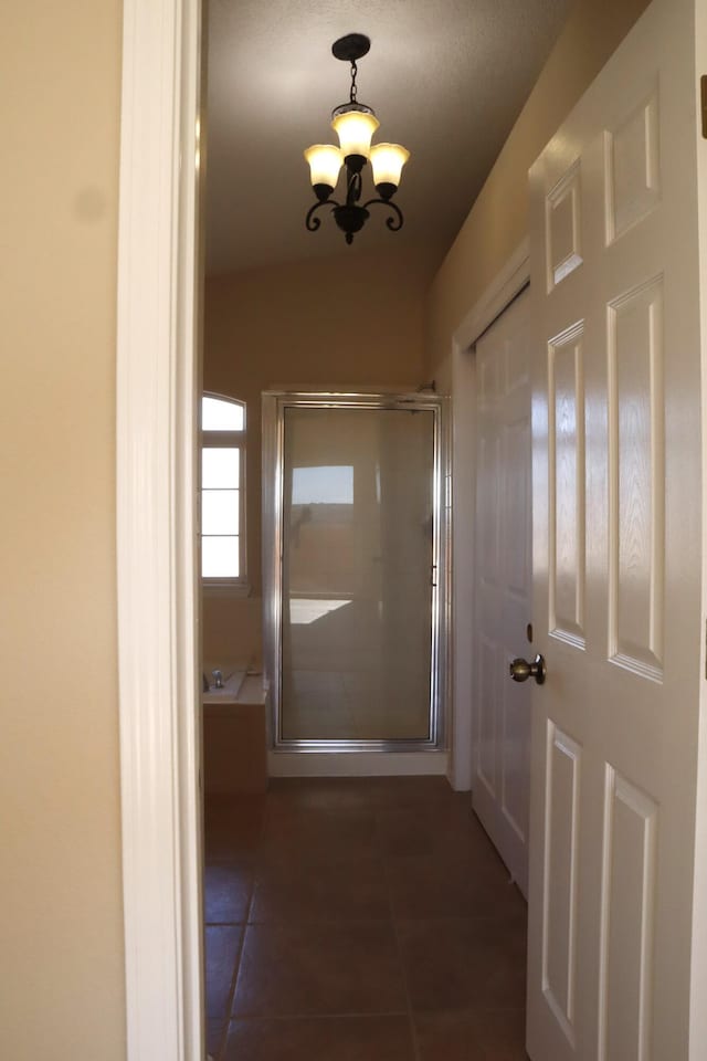 hallway with a notable chandelier and dark tile patterned floors