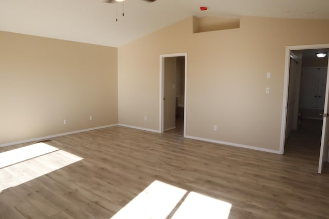 spare room featuring vaulted ceiling, ceiling fan, wood finished floors, and baseboards