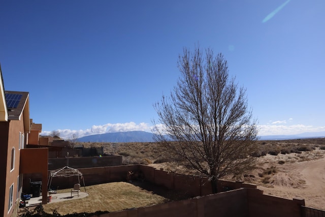 view of yard featuring fence, a mountain view, and a patio