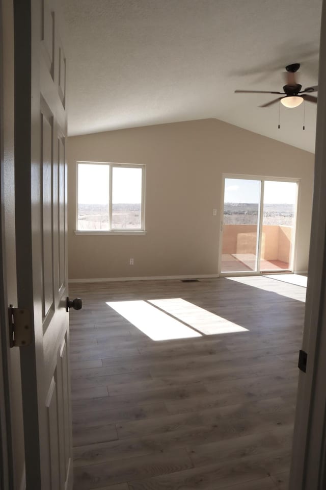 unfurnished room featuring lofted ceiling, dark wood-style flooring, a ceiling fan, and baseboards