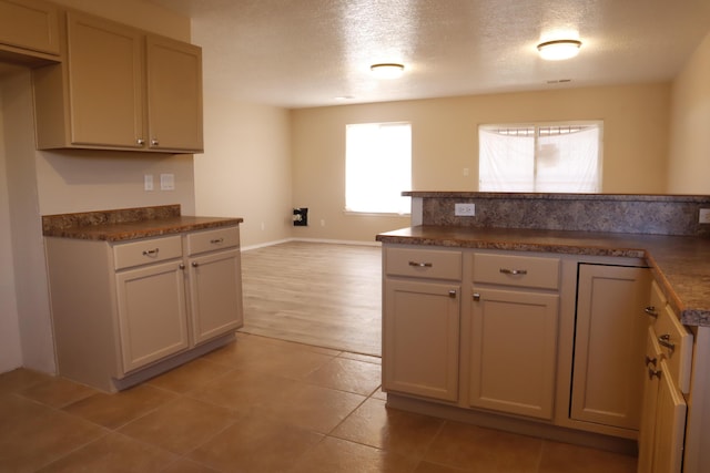 kitchen featuring open floor plan, light tile patterned floors, a textured ceiling, and dark countertops