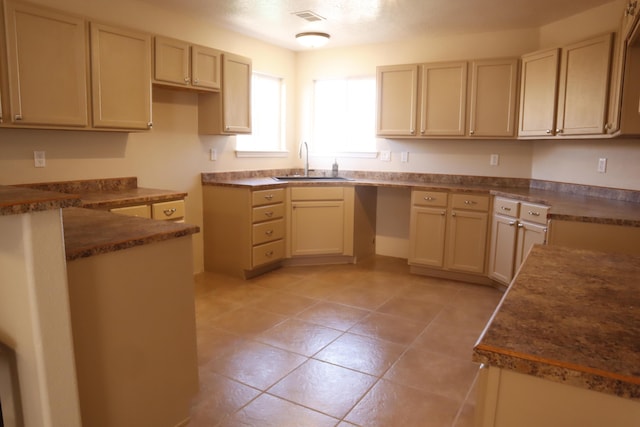 kitchen featuring visible vents, dark countertops, cream cabinets, a sink, and light tile patterned flooring