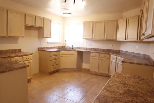 kitchen with dark countertops, light tile patterned floors, visible vents, and a sink