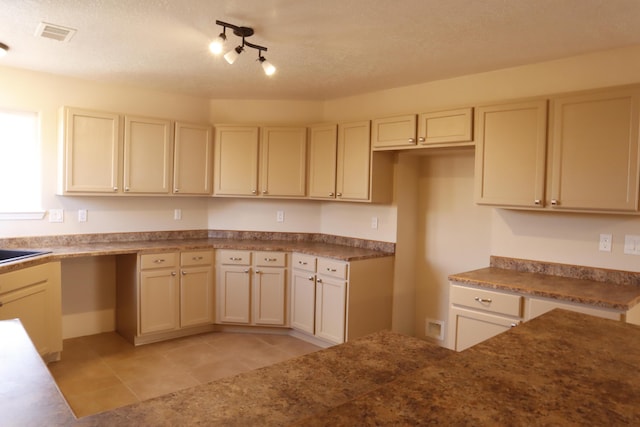 kitchen with cream cabinets, light tile patterned flooring, and visible vents