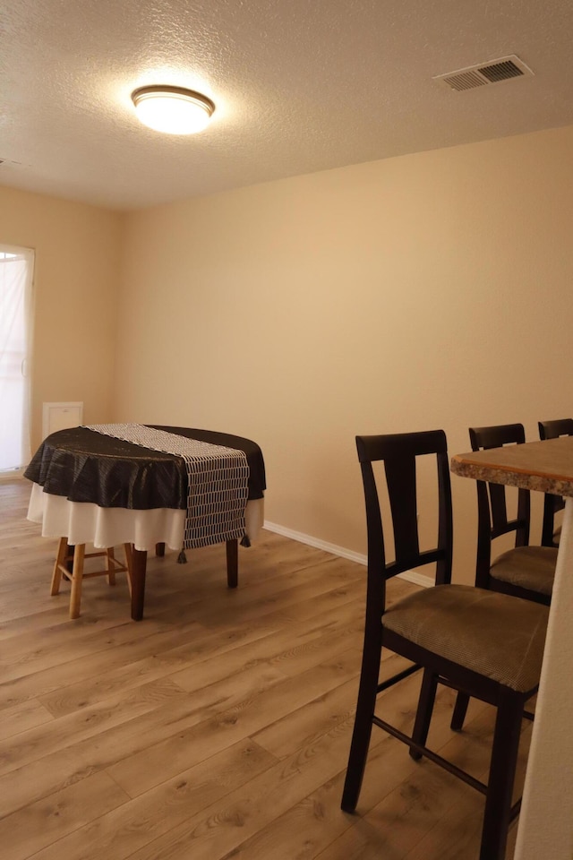 interior space with a textured ceiling, baseboards, visible vents, and light wood-style floors