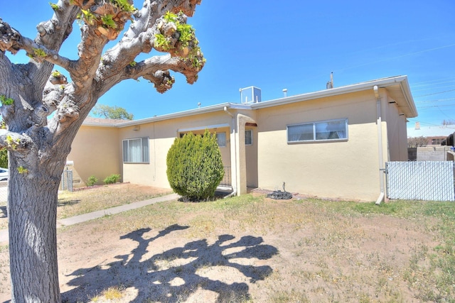 back of house featuring fence and stucco siding