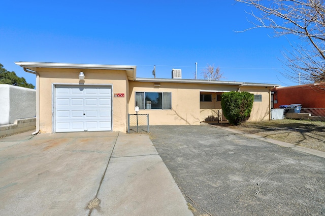 ranch-style house featuring an attached garage, driveway, and stucco siding