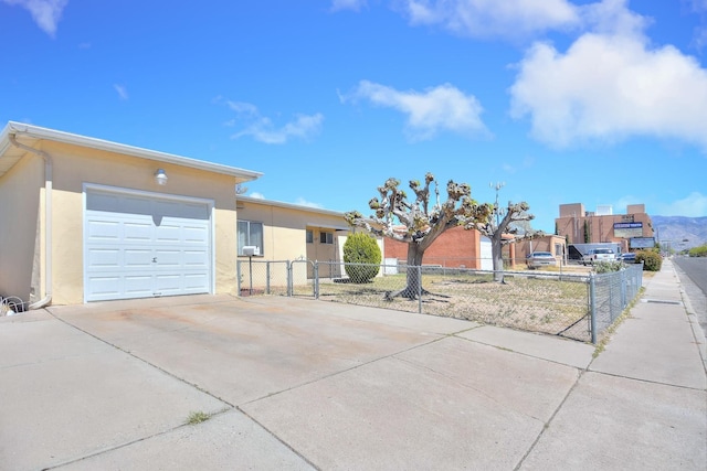 view of front of property featuring a garage, driveway, fence, and stucco siding