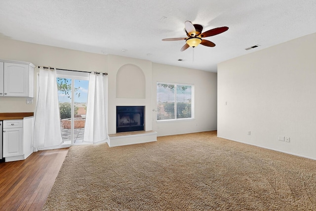 9801 Basha St NW, Albuquerque, NM 87114 - unfurnished living room with a fireplace with raised hearth, a ceiling fan, and a textured ceiling