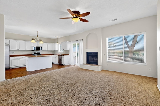 9801 Basha St NW, Albuquerque, NM 87114 - kitchen with appliances with stainless steel finishes, open floor plan, white cabinets, dark colored carpet, and a ceiling fan