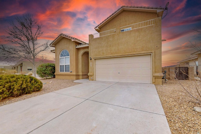 9801 Basha St NW, Albuquerque, NM 87114 - mediterranean / spanish home with concrete driveway, stucco siding, an attached garage, a tile roof, and a balcony